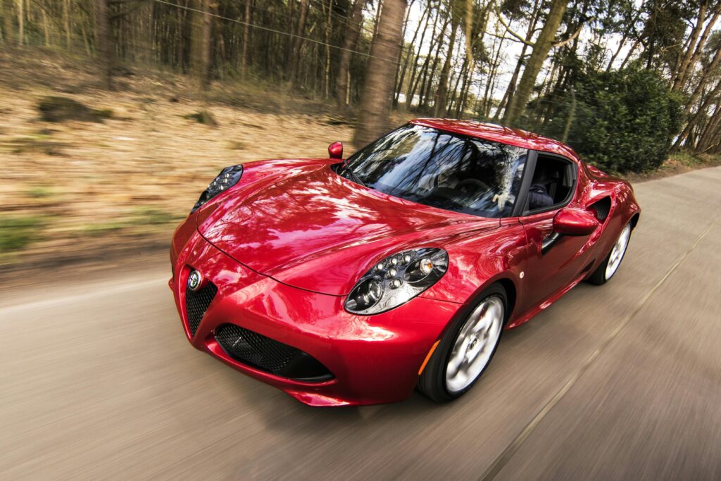 A sleek red sports car driving fast on a forest road, showcasing speed and luxury. Acessórios Automotivos