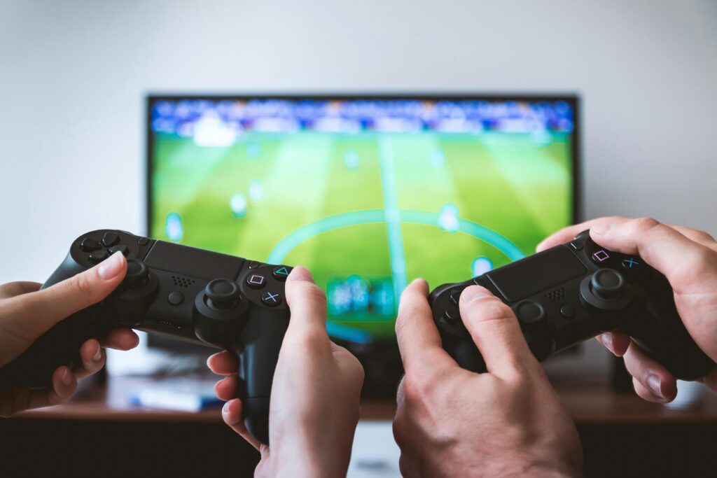 Close-up of hands holding gaming controllers in front of a TV. Engaged in a video gaming session. Smart TV